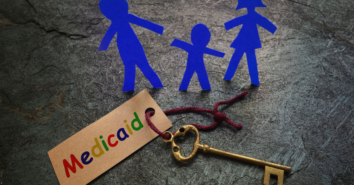 Medicaid written on a brown keychain with an old style key and three cut out figures in blue